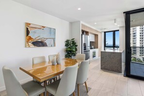 Una cocina moderna con refrigerador, horno y comedor con mesa y sillas.