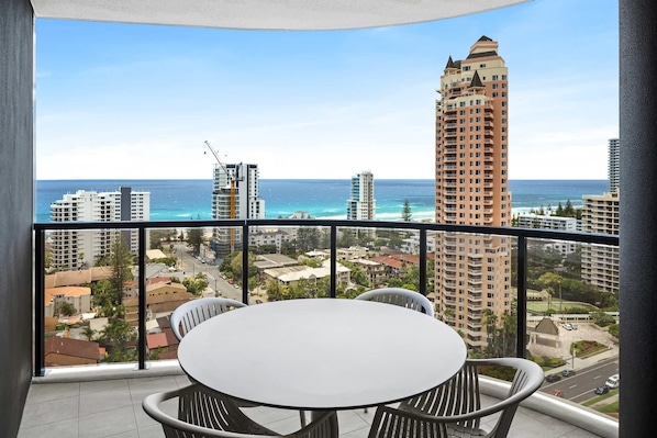 A balcony with a view of the ocean and surrounding buildings.