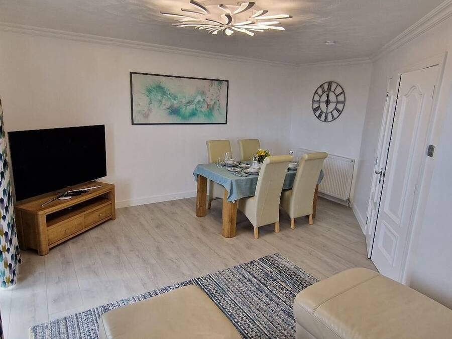 A living room with a TV, dining table, chairs, and a sofa.