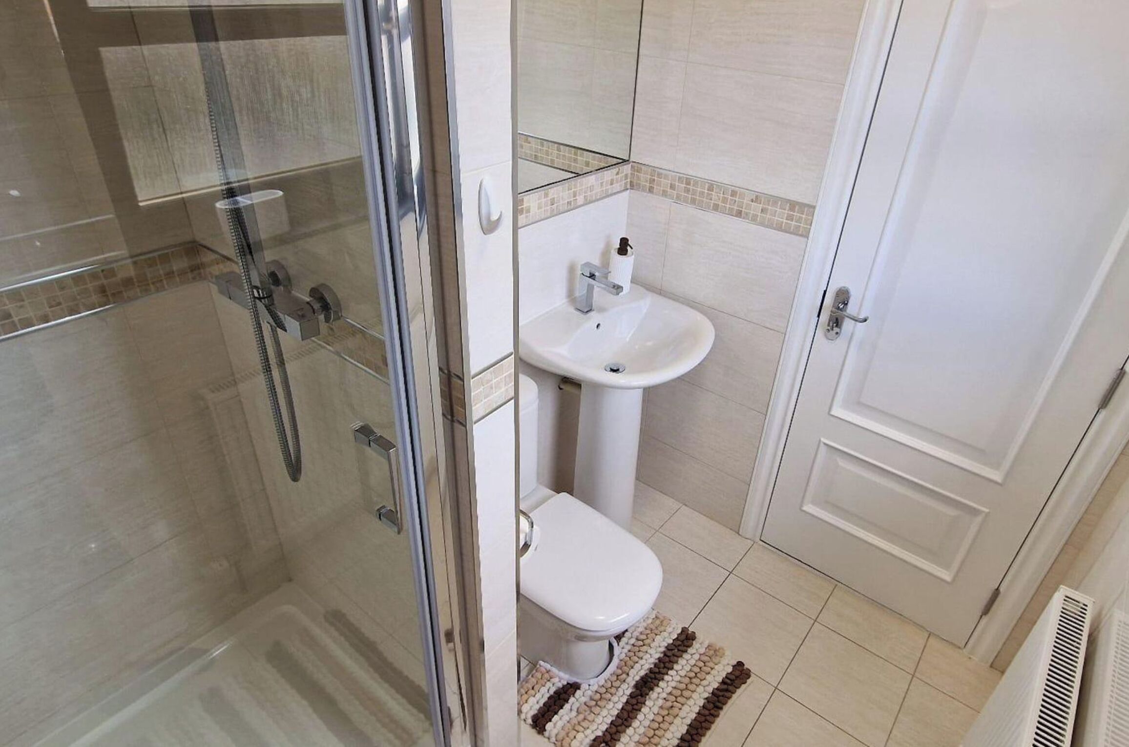 A bathroom with a glass-enclosed shower, a pedestal sink, and a toilet.