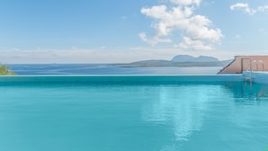 Une piscine d’un bleu éclatant, avec une vue sur la mer et les montagnes en arrière-plan.