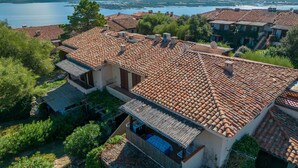 Une villa avec un toit en tuiles, un balcon et une vue sur un lac et des montagnes.