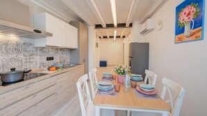 Une cuisine moderne avec des meubles blancs, un plan de travail en bois et un coin repas comprenant des chaises blanches et une table en bois.