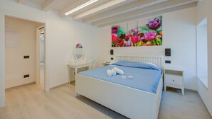Une chambre à coucher comprenant un lit, des tables de chevet, une commode, un miroir et un radiateur fixé au mur.
