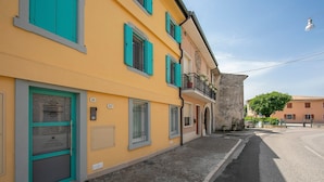 Une rue étroite bordée d’immeubles jaunes, une porte avec une enseigne et un chemin pavé.