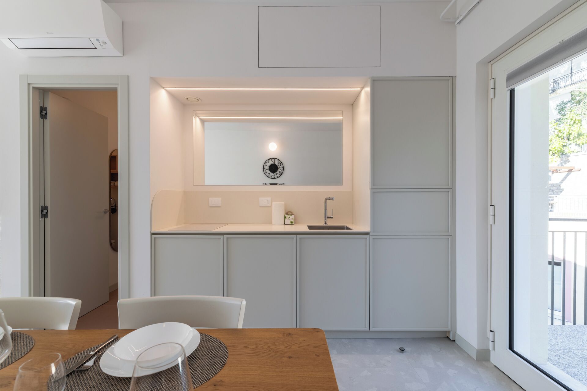 Une cuisine moderne dotée d’un évier encastré, d’un miroir au-dessus du plan de travail et d’un coin repas avec une table et des chaises.