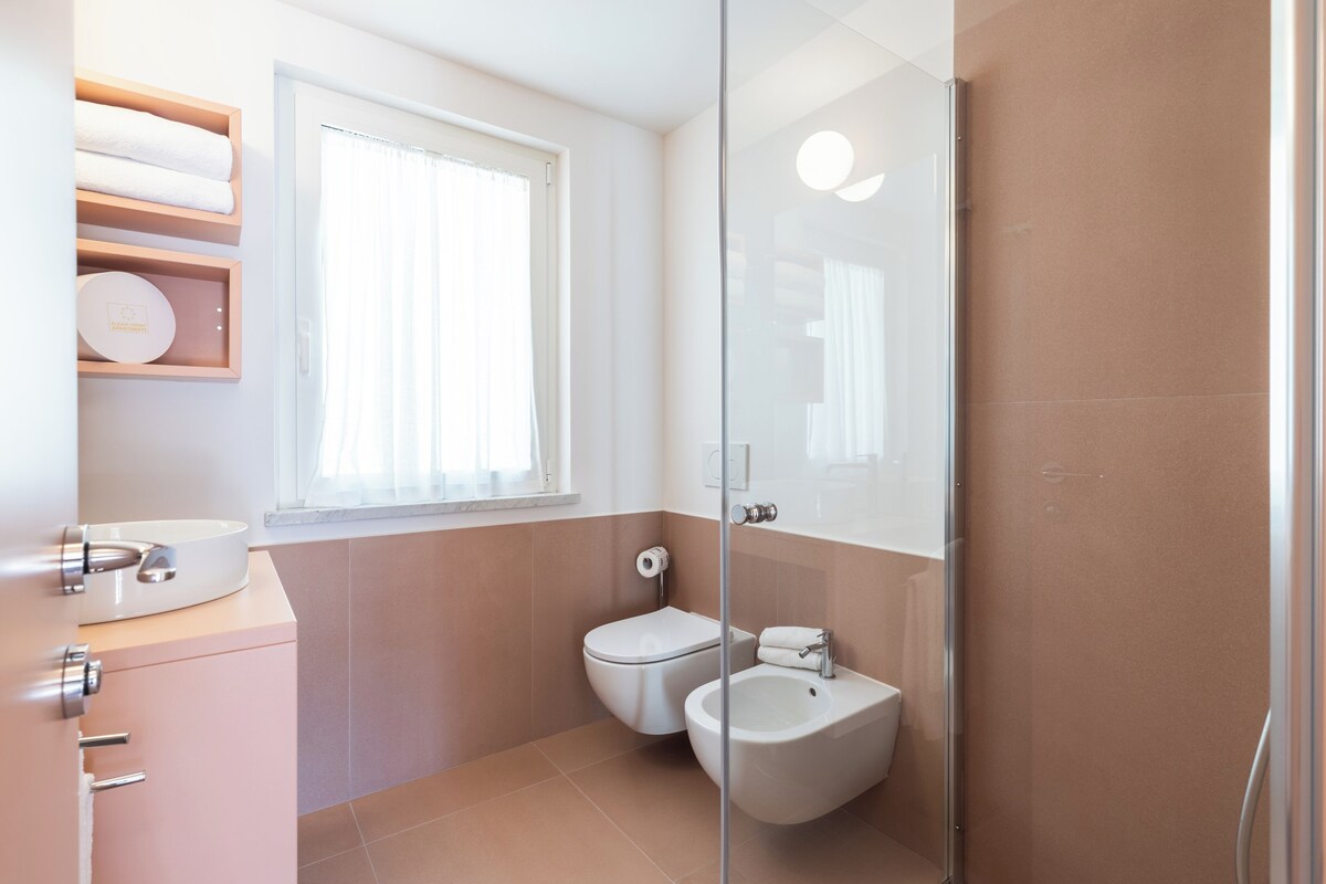 Une salle de bain moderne équipée de toilettes, d’un bidet et d’une douche à parois de verre.