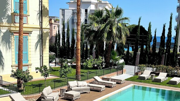 Zona de piscina con sillas de descanso y terraza de madera.