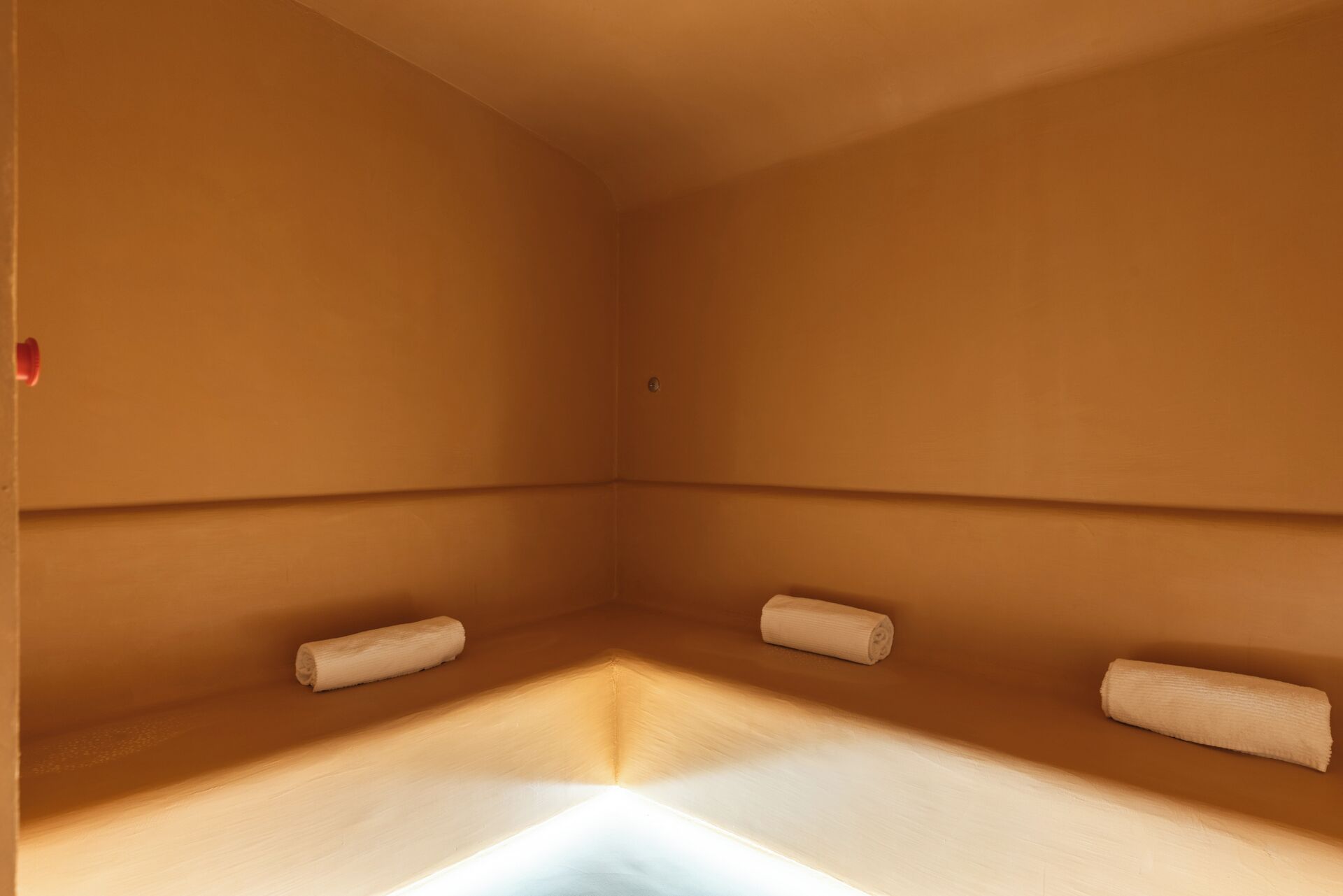 Un cuarto de spa con una cama individual, una mesita y un dispensador de toallas en la pared.