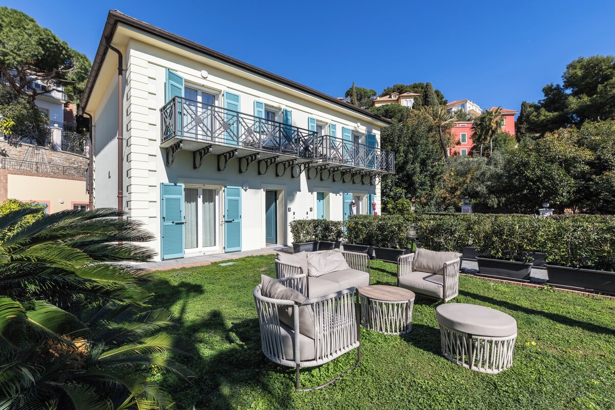 A two-story building with balconies and a well-maintained garden with outdoor furniture.