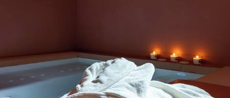 A room with a massage table, a white towel, and candles.