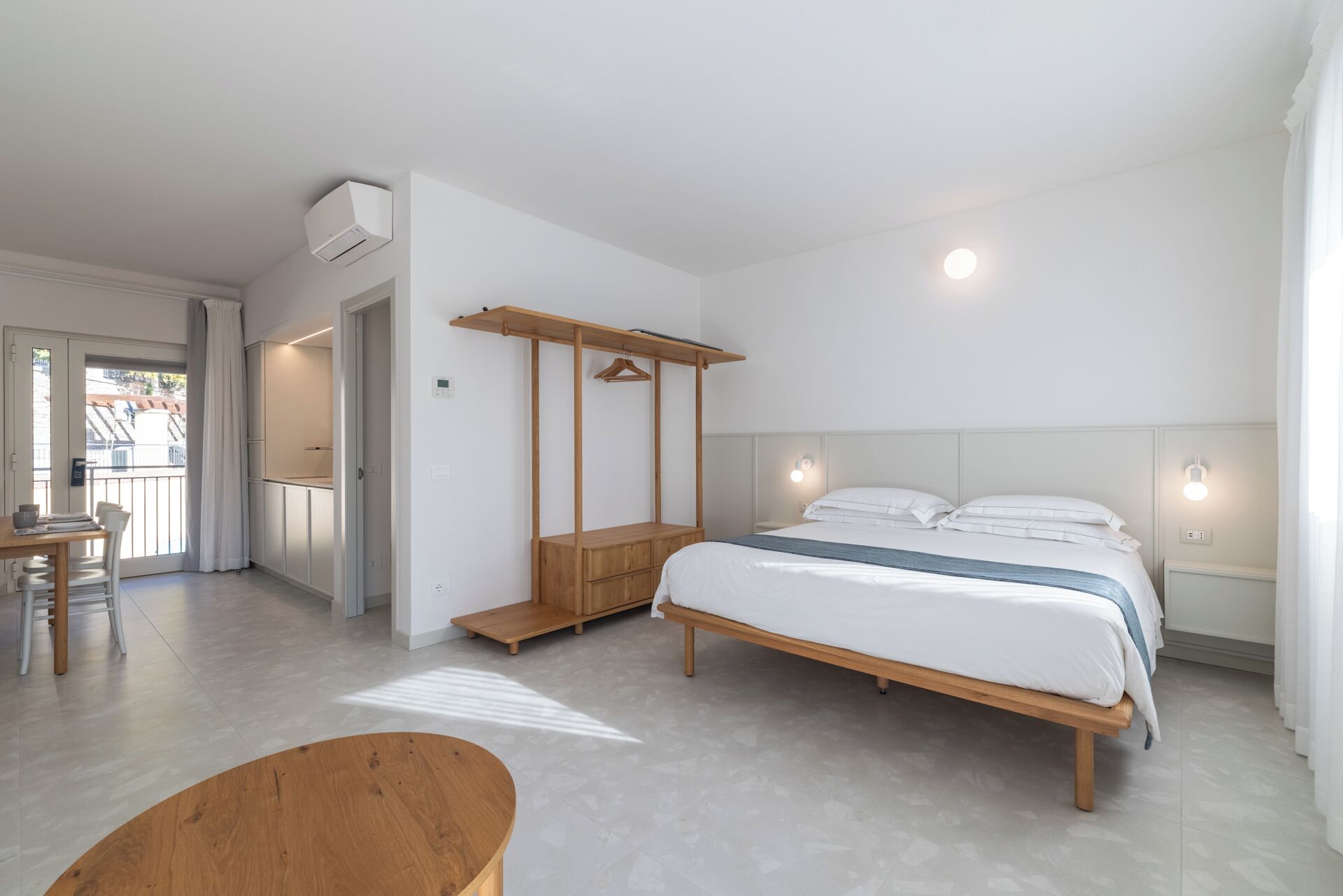Une chambre à coucher comprenant un lit, des tables de chevet, un banc en bois, une armoire et un ventilateur de plafond.
