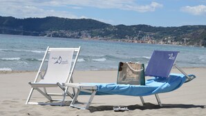 Dos sillas de playa sobre arena, con una bolsa y gafas de sol en el suelo.