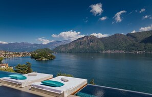 Relax by the infinity pool overlooking a serene lake and majestic mountains.