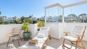 A sunlit balcony with two lounge chairs, a wicker chair, and potted plants. - Calahonda Golf in Calahonda (Mijas)