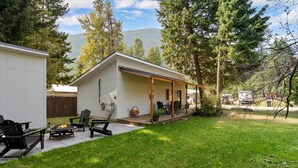 Une maison moderne dotée d’un patio couvert, d’un espace salon extérieur et d’un foyer.