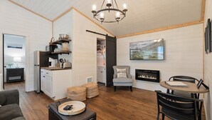 Un salon moderne avec une cheminée, un coin repas et une cuisine dotée d’étagères en bois.