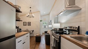 Une cuisine moderne avec des meubles blancs, une hotte en acier inoxydable et un plan de travail en bois.