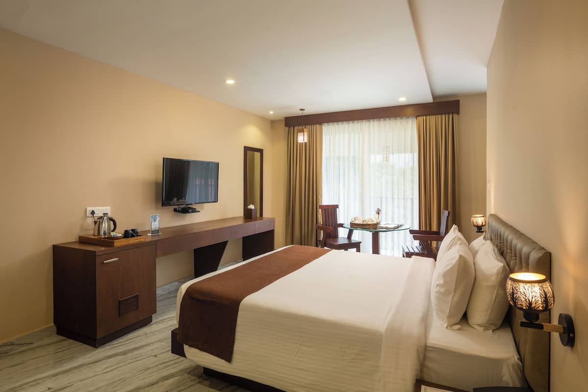 Une chambre d’hôtel avec un grand lit, un bureau avec une télévision, une petite table et une chaise.