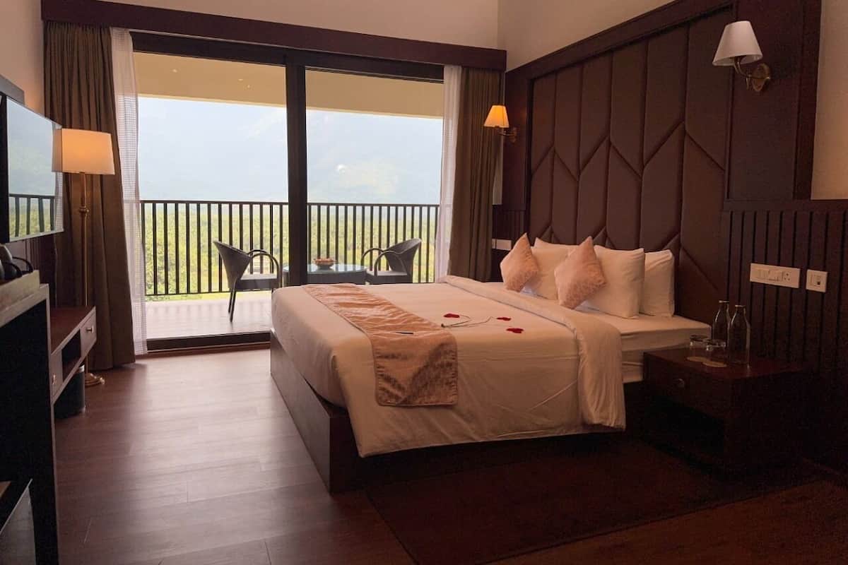 Une chambre d’hôtel avec un grand lit, une télévision, un bureau et un balcon avec vue.