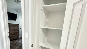 A hallway with a white door leading to a room with a built-in shelving unit. - Pitcher's Paradise Apt 1 - All Star Baseball Rentals (Oneonta)