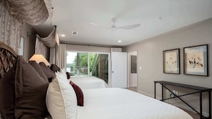 A bedroom with two beds, a ceiling fan, and a view of the outdoors.
