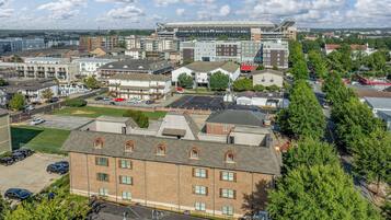 A multi-story building with a brick facade, a parking lot, and a large stadium in the background.