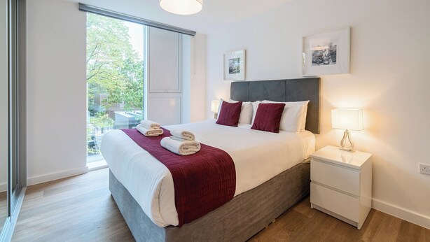 Una camera da letto moderna con un letto grande, un comodino e vista sull'esterno.