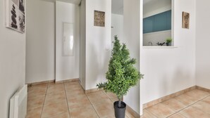 A hallway with a potted plant, a door, and a wall-mounted sign.