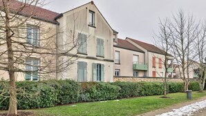 A residential building with a symmetrical facade, multiple windows, and a well-maintained lawn.