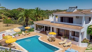 Ein zweistöckiges Haus mit Swimmingpool, Sitzgelegenheit im Freien und Solarwasseranschluss.