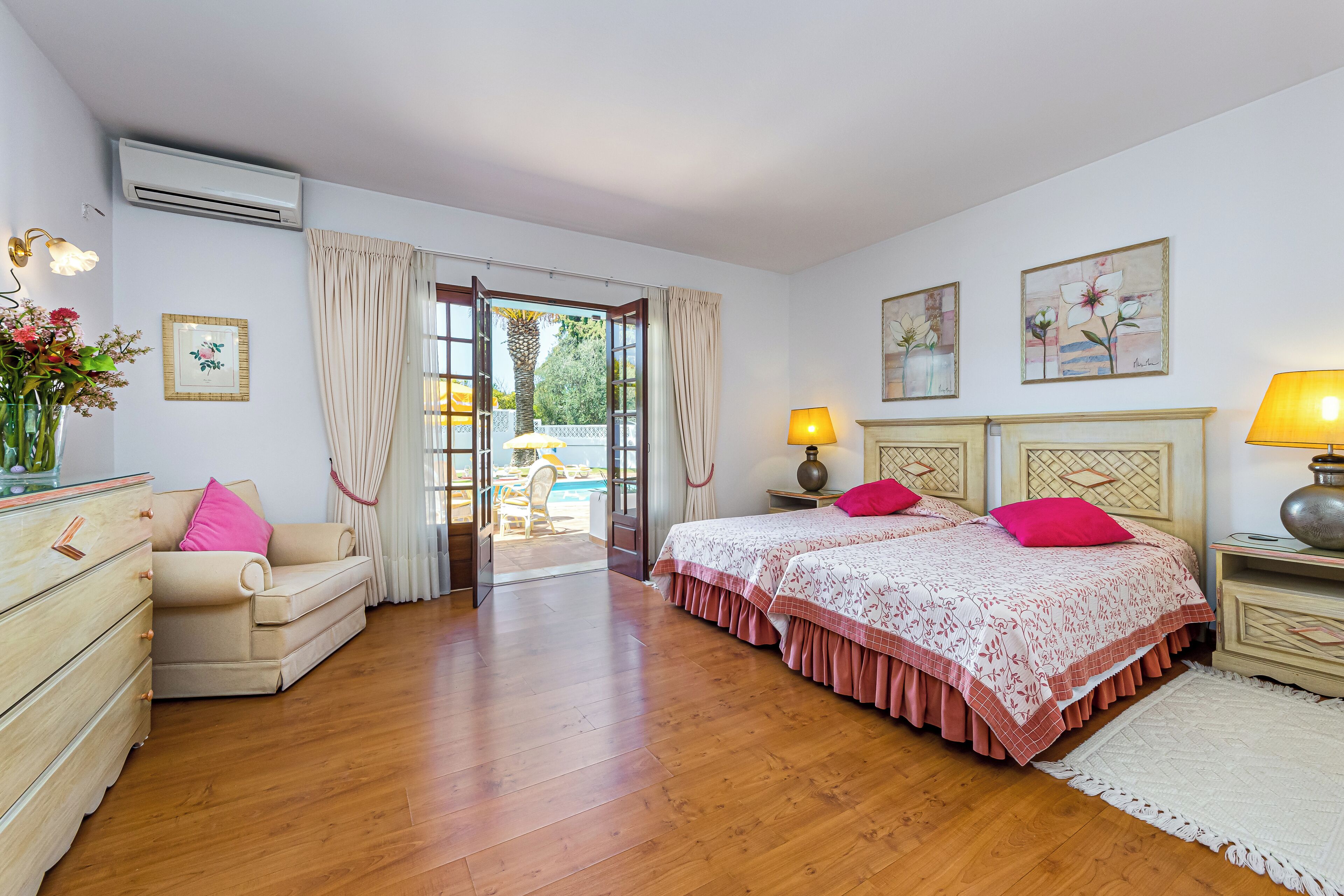 A bedroom with two beds, a dresser, a nightstand, and a window with curtains.