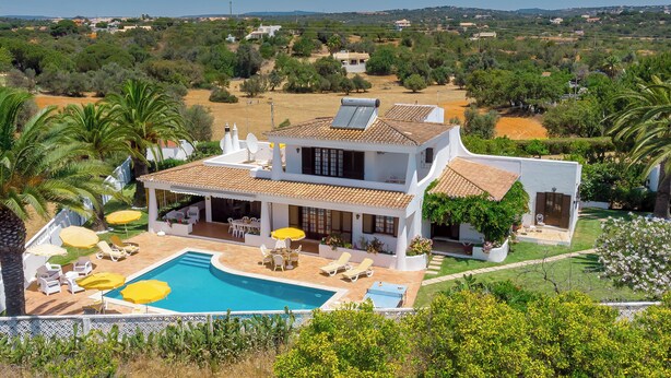 Eine moderne Villa mit Swimmingpool, Sitzgelegenheiten im Freien und Blick auf die umliegende Landschaft.