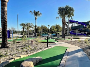 A golf course with a water slide and palm trees.