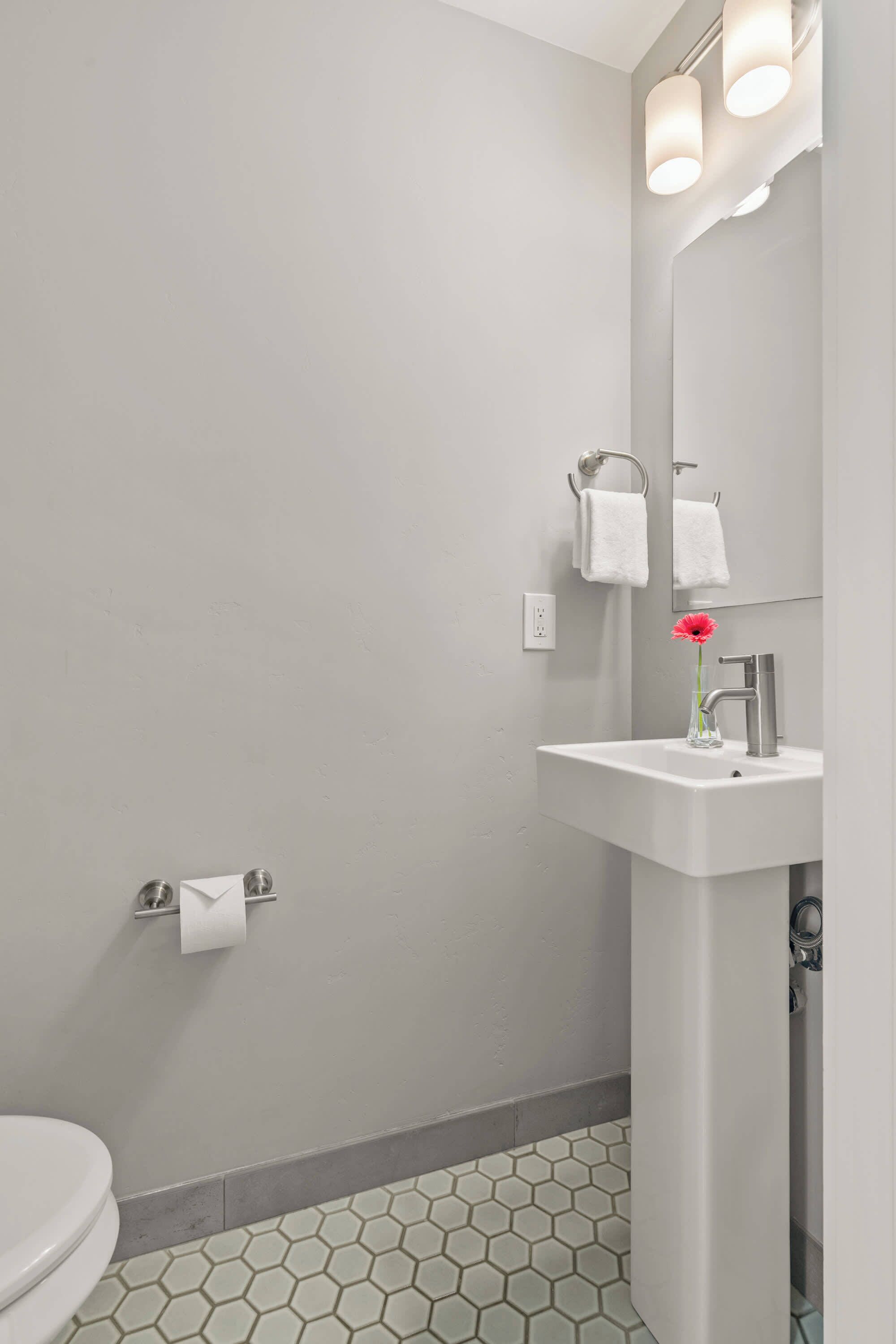 A bathroom with a toilet, a sink with a mirror, and a towel rack.