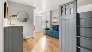 A modern room with a blue sofa, a grey wardrobe, and a round mirror on the wall. - Modern Pacific Beach Paradise (San Diego)