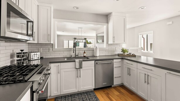 A modern kitchen with white cabinets, stainless steel appliances, and a wooden floor. - Modern Pacific Beach Paradise (San Diego)