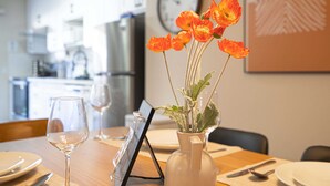 Uma mesa de jantar com um vaso de flores, uma taça de vinho e um suporte para cardápio.