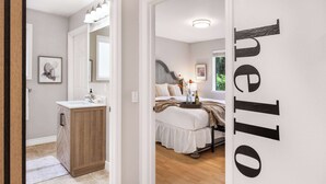 Un dormitorio con cama, mesita de noche y un espejo grande. Incluye un baño con lavabo y armario.