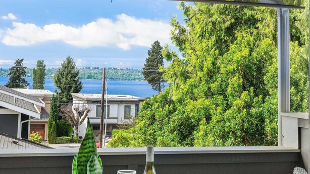 A balcony with a table, a potted plant, a wine glass, and a bottle of wine. - Modern 2BR/2BA Kirkland Home, Walk to Beach Park (Kirkland)