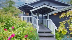 A modern house with a covered porch and a wooden staircase leading to the entrance. - Modern 2BR/2BA Kirkland Home, Walk to Beach Park (Kirkland)