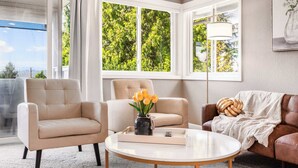 A modern living room with a beige sofa, a round coffee table, and a vase of flowers. - Modern 2BR/2BA Kirkland Home, Walk to Beach Park (Kirkland)