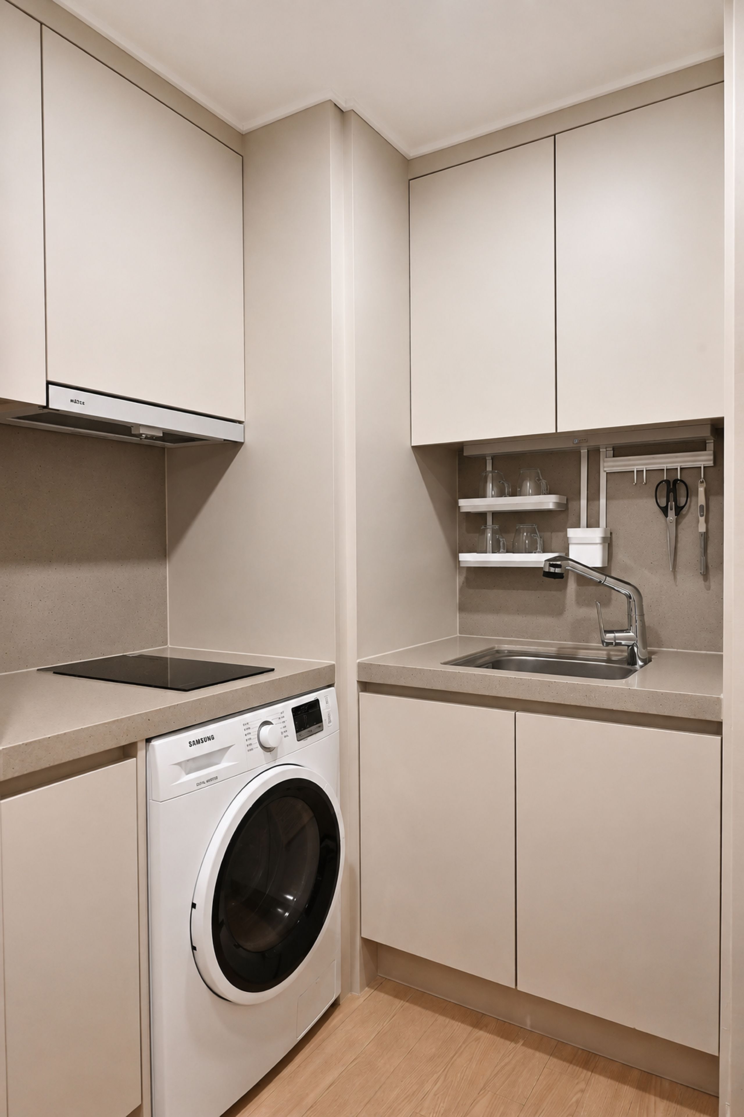 Een praktische keuken met een inbouw wasmachine en droger, een spoelbak en een aanrecht.