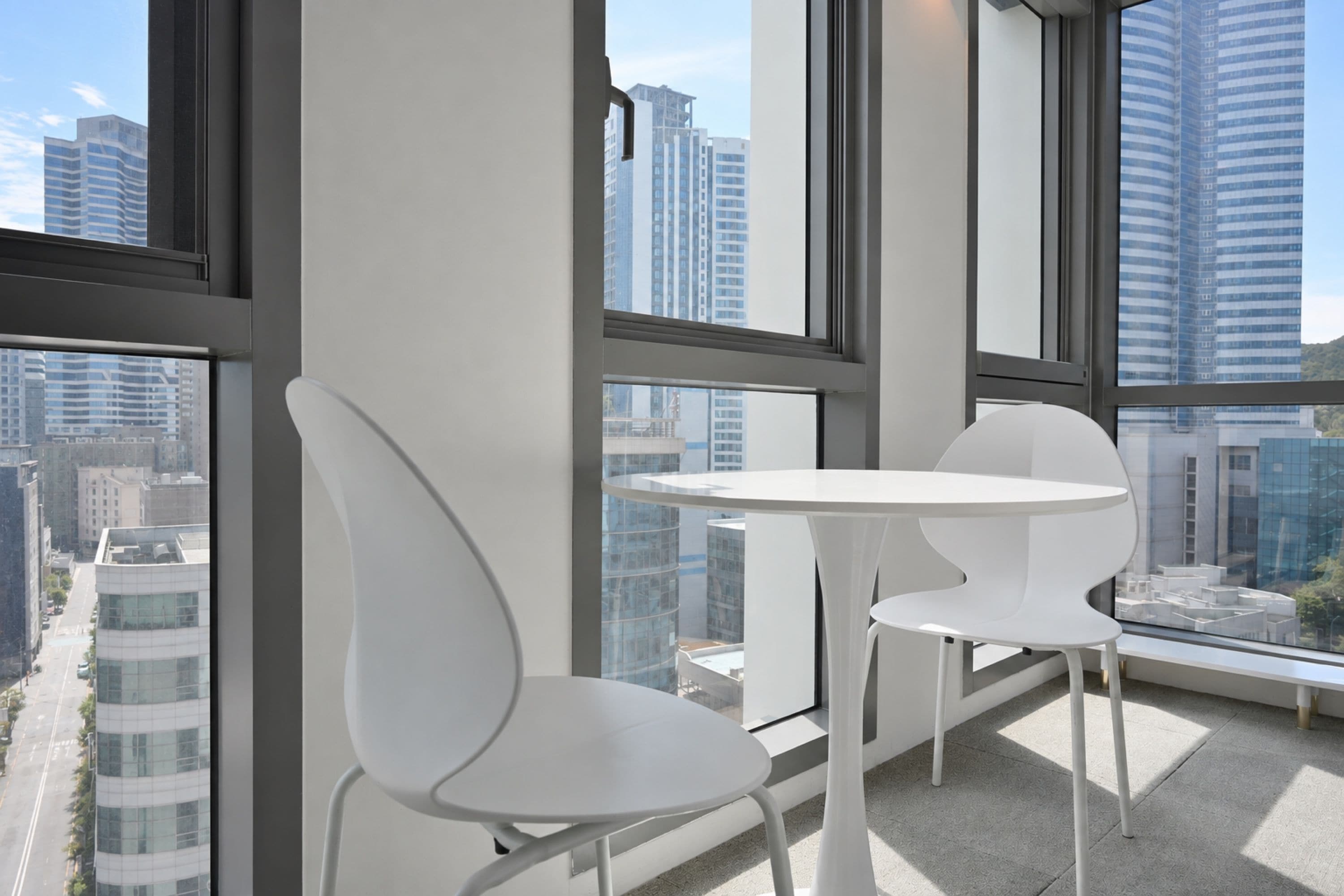 A modern interior with a balcony, white chairs, and a table.