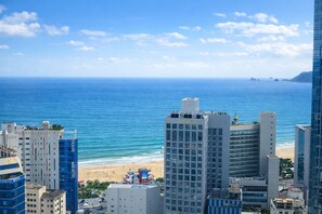 Un paisaje urbano costero con edificios altos, una playa y cielos azules despejados.
