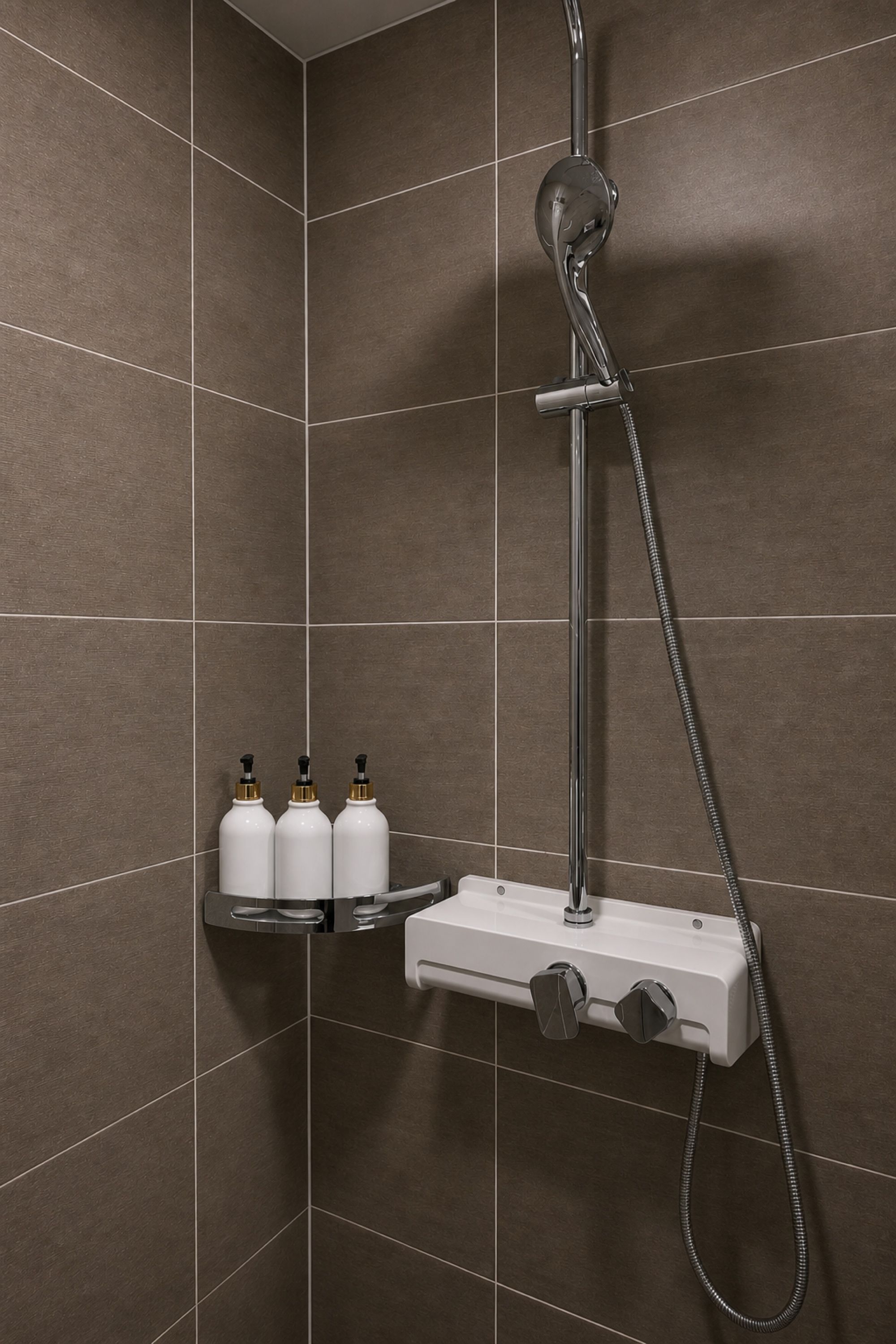 A shower area with a handheld showerhead, a wall-mounted faucet, and a soap dispenser shelf.