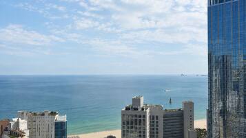 A coastal cityscape with modern buildings, a beach, and a clear sky.
