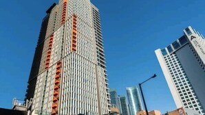 A tall, modern skyscraper with a unique facade featuring vertical orange accents. - Haeundae Lamer Stay (Busan)
