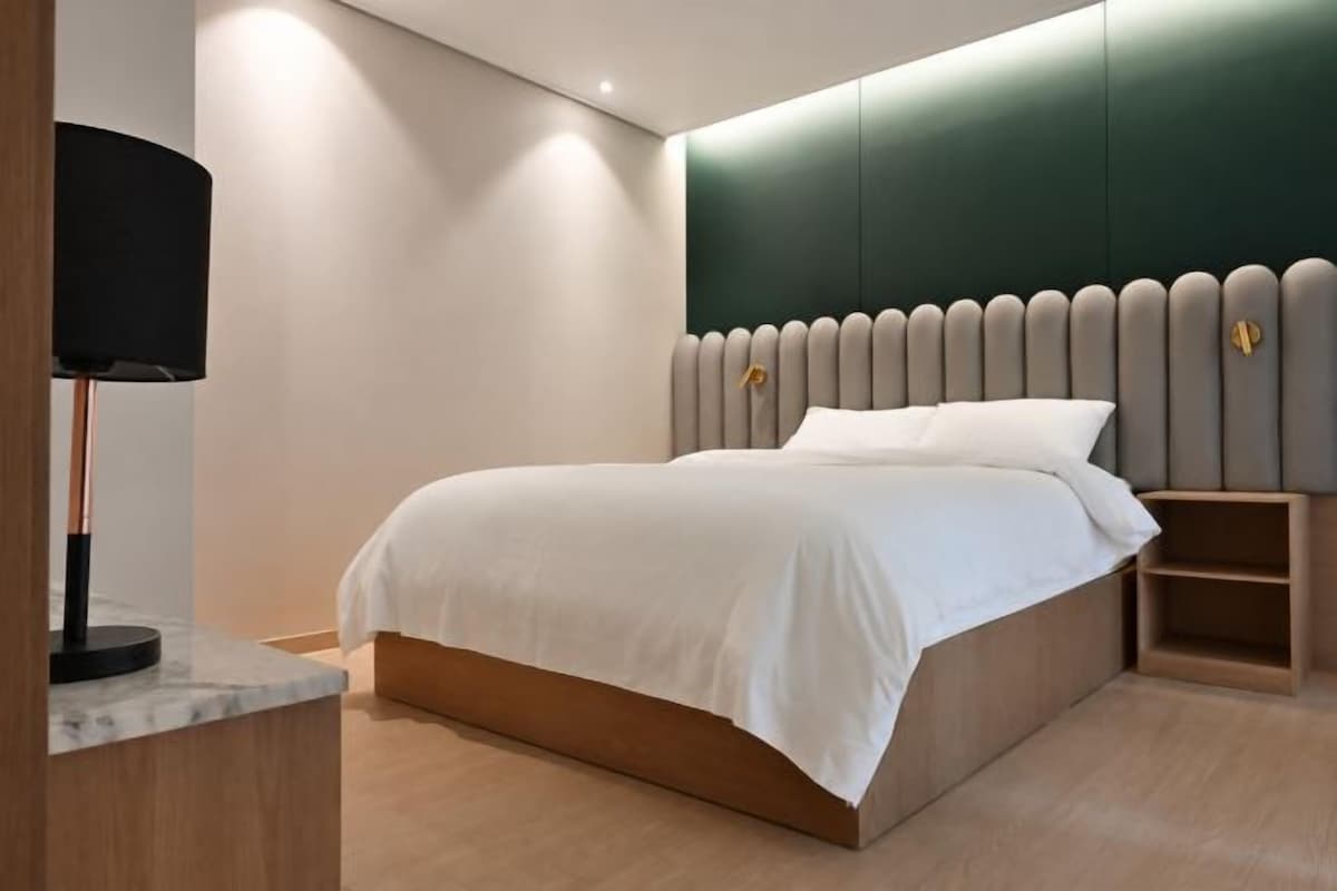 Un dormitorio moderno con cama, mesita de noche y lámpara.