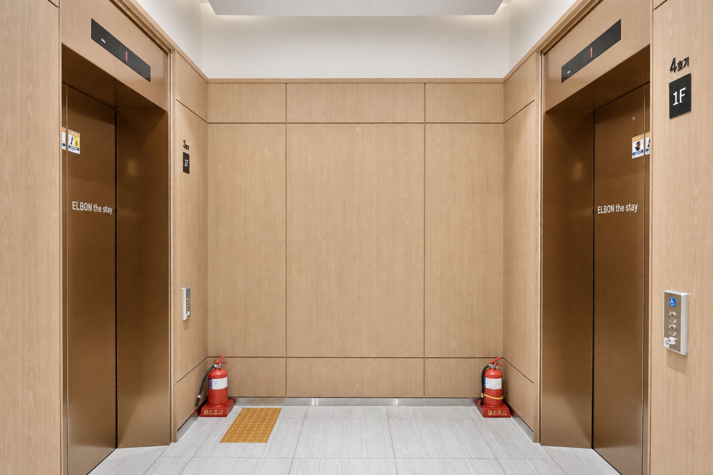 An elevator with wooden walls, floor indicators, and fire extinguishers.